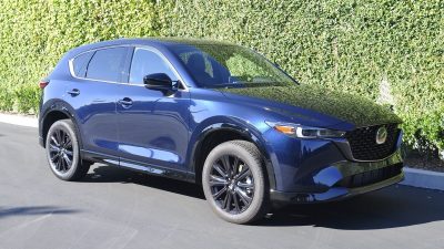 2024 Mazda CX-5 Turbo in blue next to an ivy wall.