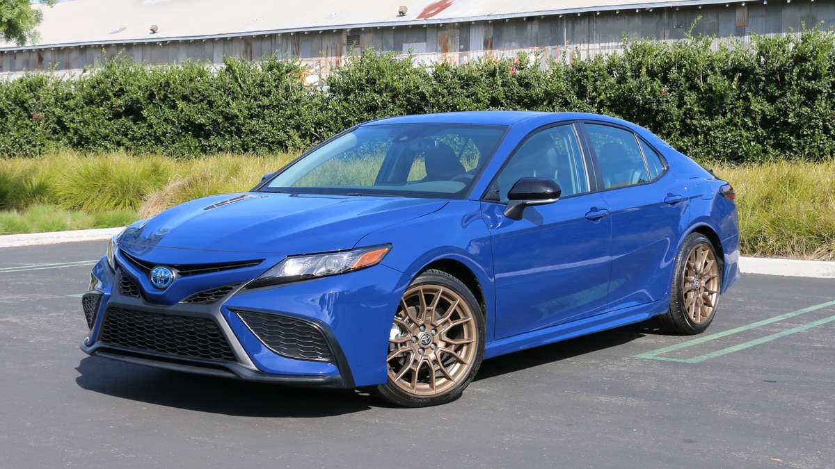 2023 Toyota Camry Hybrid Nightshade near bushes.