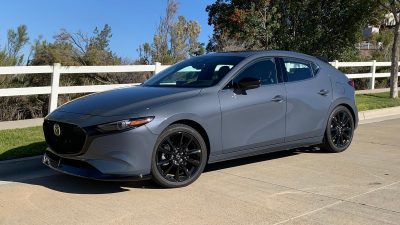 2024 Mazda3 2.5 Turbo Premium Plus in Polymetal Grey Metallic. near a white fence.