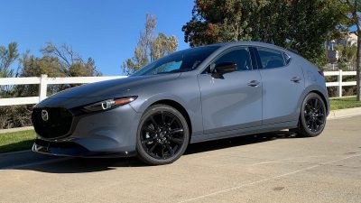 2024 Mazda3 2.5 Turbo Premium Plus in Polymetal Grey Metallic. near a white fence.