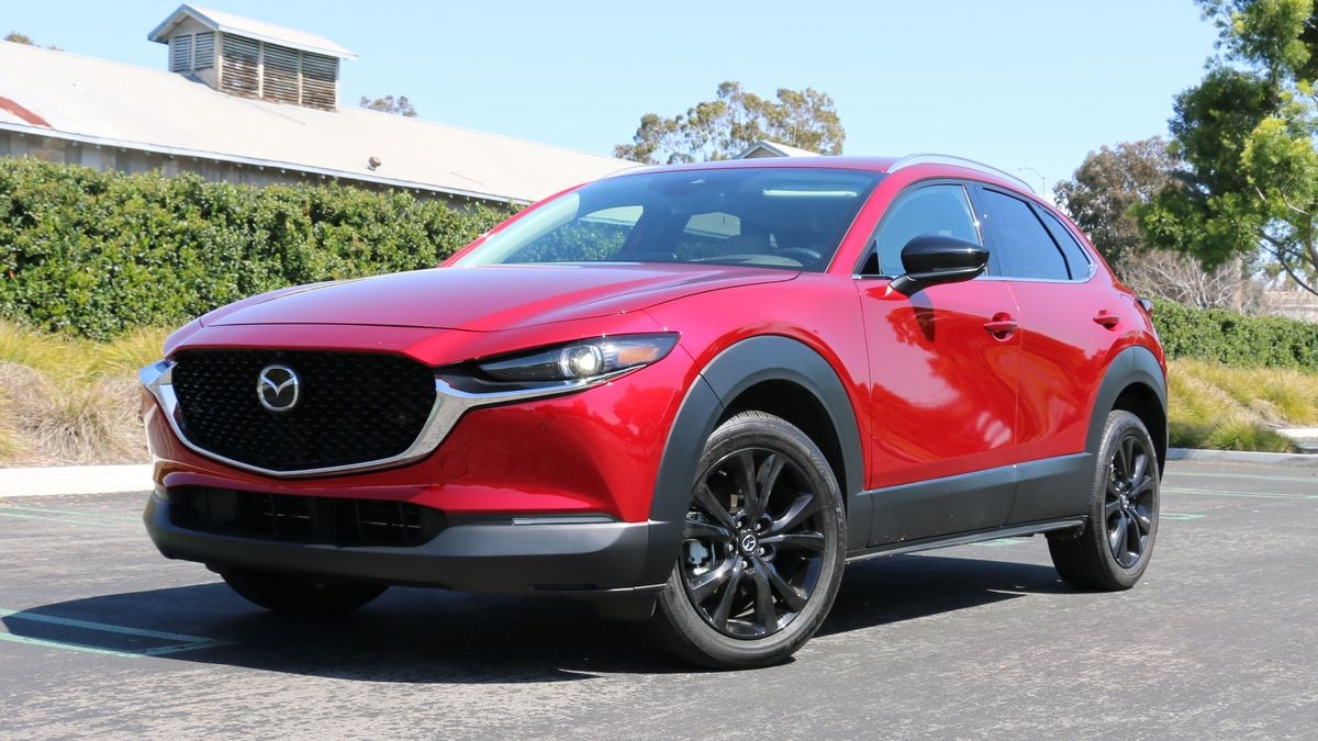 2024 Mazda CX-30 in red with bushes and a barn in the background.