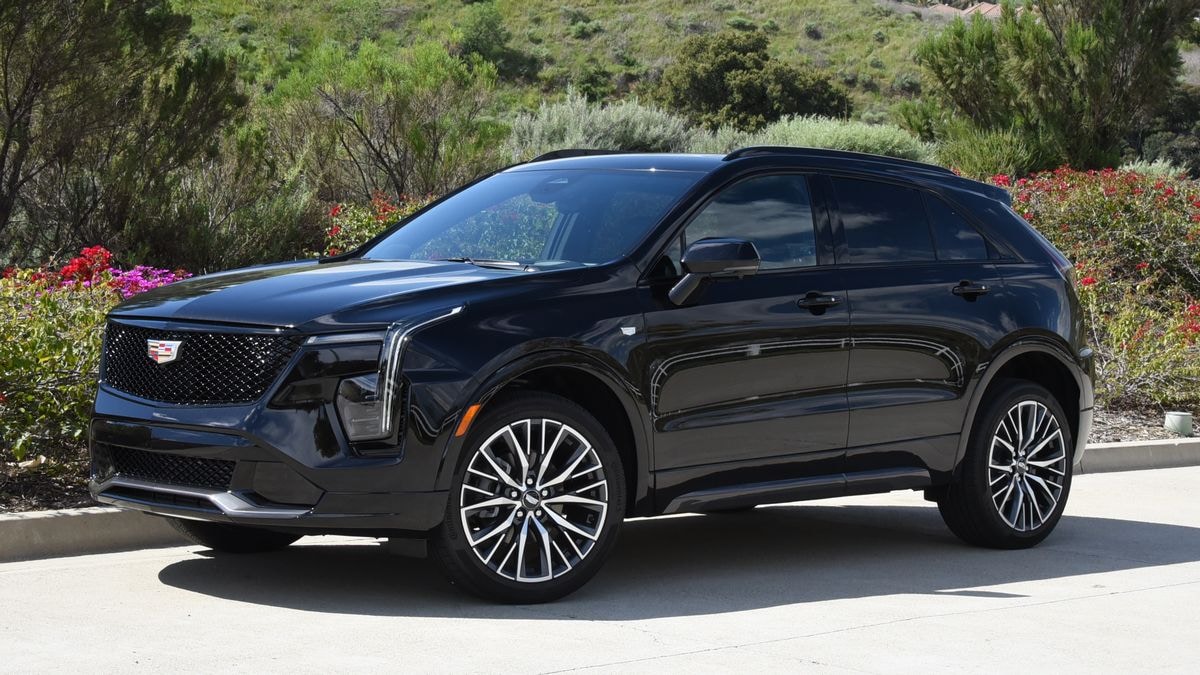 2024 Cadillac XT4 in black with shrubs in the background.